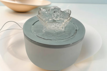 Small round gray electronic device with a clear crystal-like top on a light background